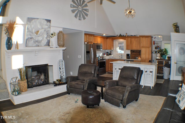 living room with high vaulted ceiling, sink, a notable chandelier, and a fireplace