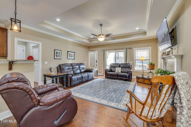 living room featuring crown molding, ceiling fan, a tray ceiling, and light hardwood / wood-style floors