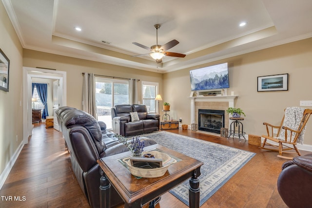 living room featuring crown molding, hardwood / wood-style flooring, a raised ceiling, and ceiling fan