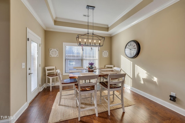 dining area featuring crown molding, dark wood-type flooring, and a tray ceiling