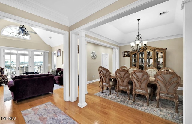 dining area featuring french doors, ceiling fan with notable chandelier, crown molding, light hardwood / wood-style flooring, and ornate columns