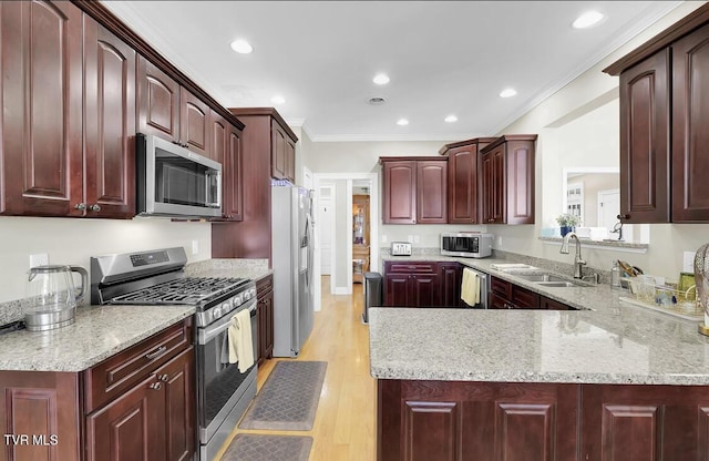 kitchen featuring crown molding, sink, light hardwood / wood-style flooring, kitchen peninsula, and stainless steel appliances