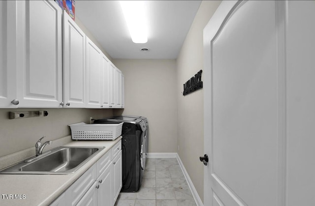 clothes washing area featuring sink, cabinets, and independent washer and dryer