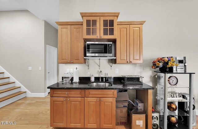 kitchen with light hardwood / wood-style floors, dark stone counters, and sink