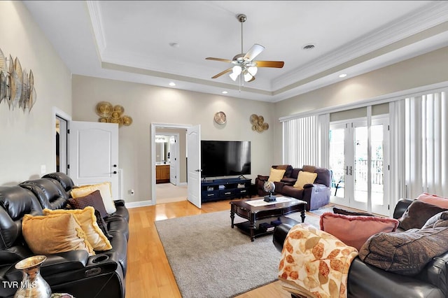 living room featuring a tray ceiling, light hardwood / wood-style flooring, ceiling fan, and crown molding