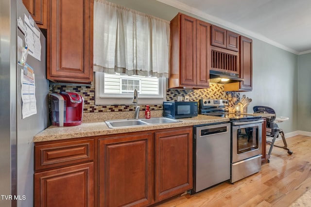 kitchen with appliances with stainless steel finishes, tasteful backsplash, crown molding, sink, and light hardwood / wood-style flooring