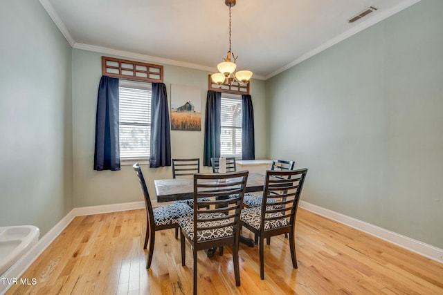 dining area featuring light hardwood / wood-style flooring, a notable chandelier, and crown molding