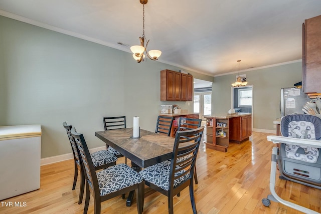 dining room featuring light hardwood / wood-style floors, crown molding, and a chandelier