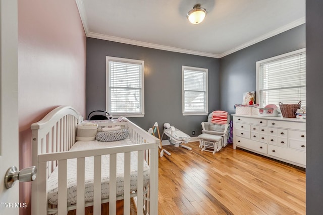 bedroom featuring light hardwood / wood-style flooring, a nursery area, and ornamental molding