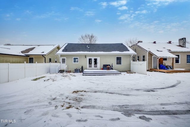 snow covered rear of property featuring french doors and a deck