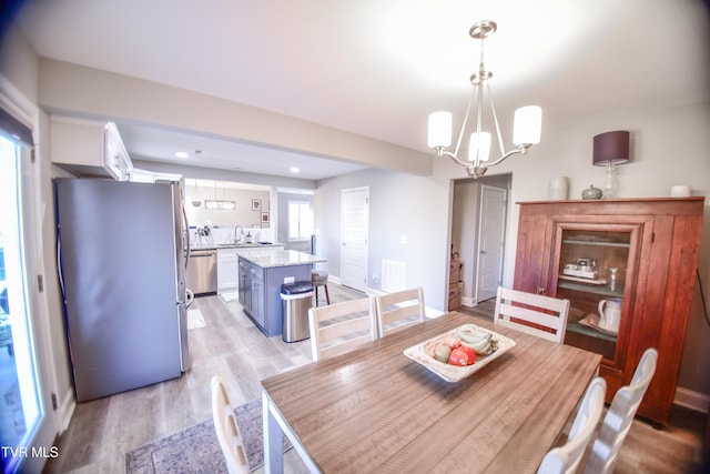 dining space with a notable chandelier, light hardwood / wood-style flooring, and sink