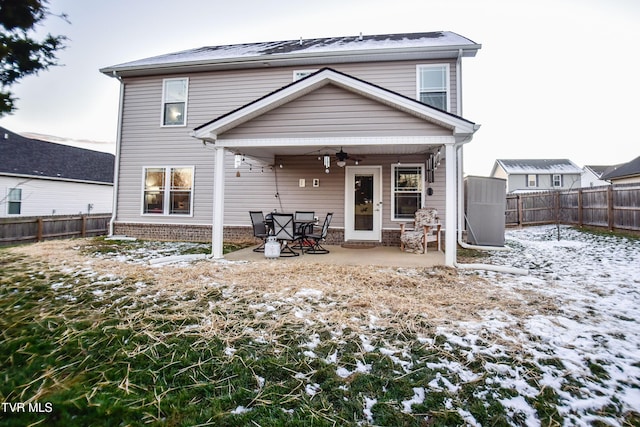 snow covered rear of property with ceiling fan and a patio