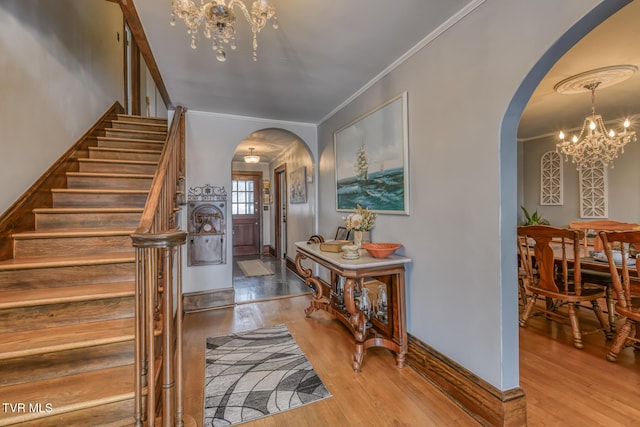 entrance foyer with hardwood / wood-style flooring, crown molding, and a chandelier