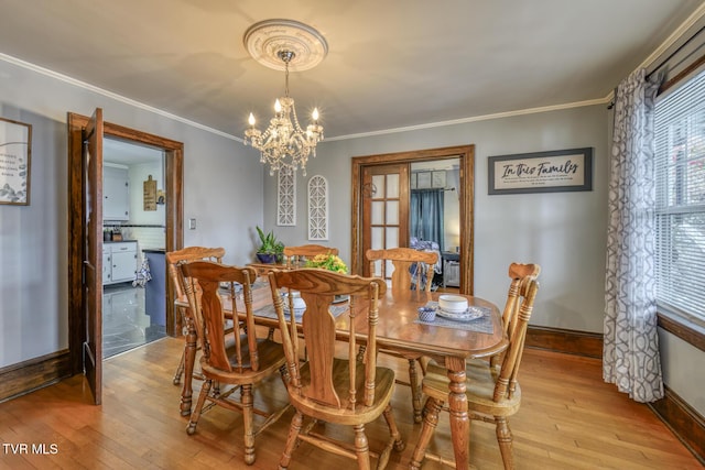 dining area with a notable chandelier, light wood-type flooring, and ornamental molding