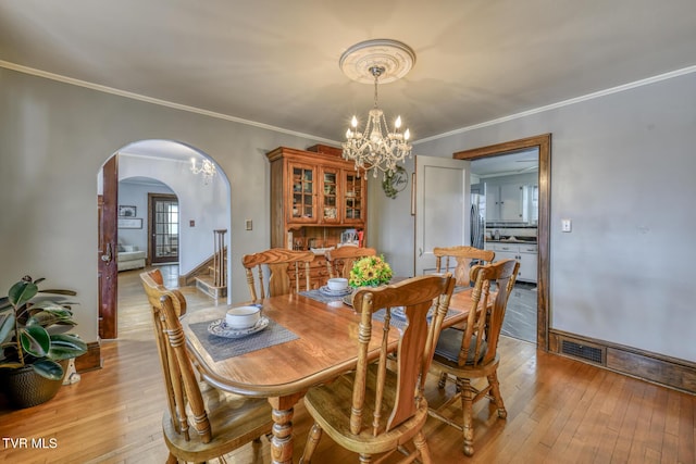 dining space featuring a notable chandelier, light wood-type flooring, and crown molding