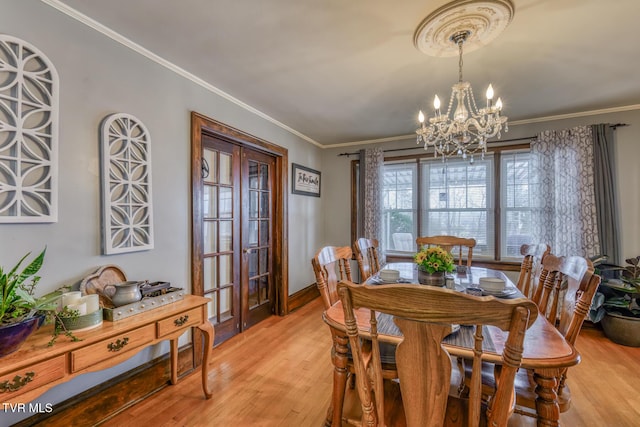 dining room featuring light hardwood / wood-style floors, ornamental molding, and an inviting chandelier