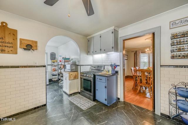 kitchen with gas range, ceiling fan with notable chandelier, tile walls, and ornamental molding