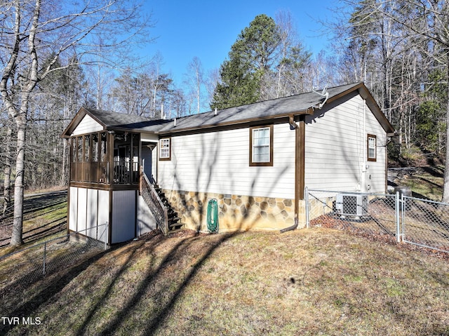 back of property featuring a lawn, central AC unit, and a sunroom