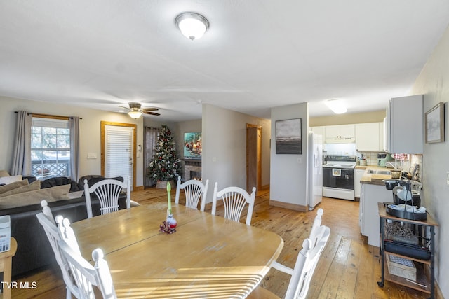 dining space with ceiling fan, sink, and light hardwood / wood-style floors