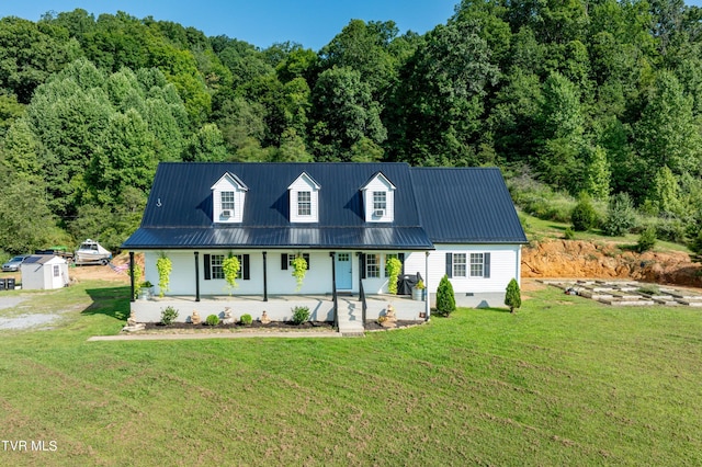 cape cod home featuring a front yard, covered porch, and a storage unit