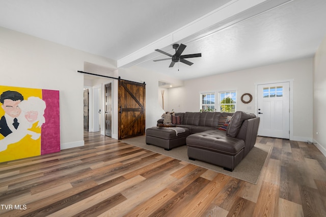 living room with wood-type flooring, ceiling fan, a barn door, and beam ceiling