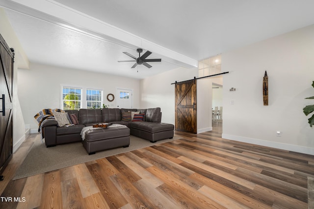 living room featuring beam ceiling, a barn door, and wood-type flooring