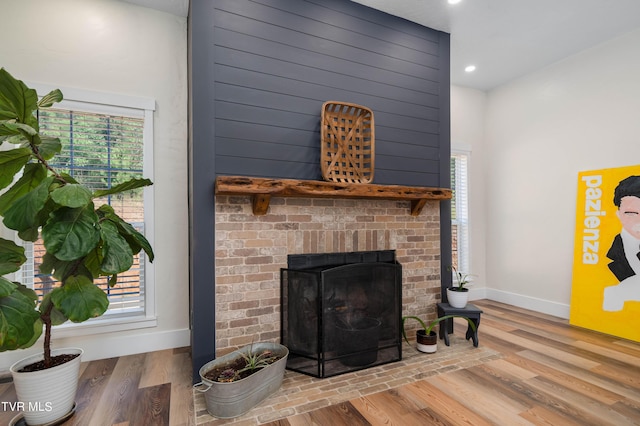 living room featuring a brick fireplace, hardwood / wood-style flooring, and plenty of natural light