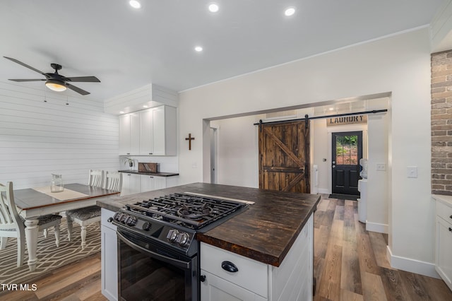 kitchen featuring a barn door, gas stove, a kitchen island, hardwood / wood-style flooring, and white cabinets