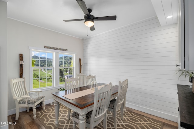 dining room with ceiling fan, wooden walls, hardwood / wood-style floors, and ornamental molding