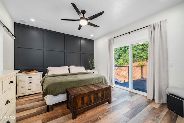 bedroom featuring access to exterior, ceiling fan, hardwood / wood-style flooring, and a barn door