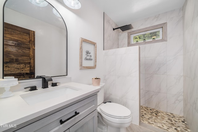 bathroom featuring tile walls, a tile shower, vanity, and toilet