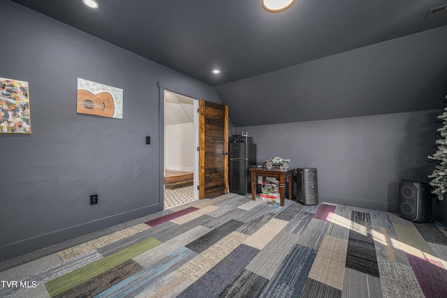 unfurnished bedroom featuring fridge, carpet, and vaulted ceiling