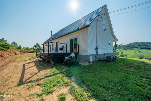 view of home's exterior featuring a deck, a yard, and central AC