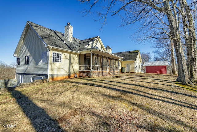 rear view of property with a chimney, a yard, and a sunroom