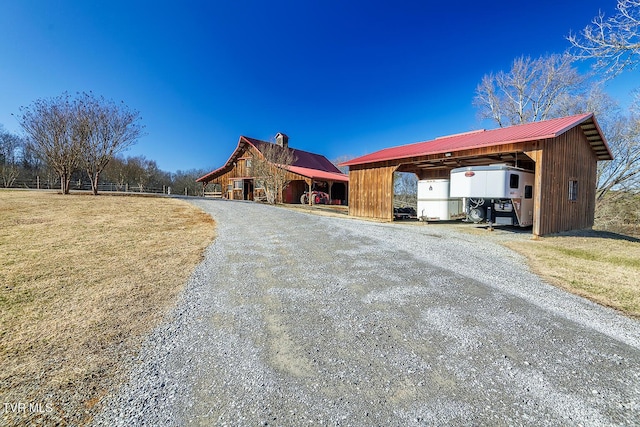 exterior space featuring metal roof, a lawn, an outdoor structure, and driveway