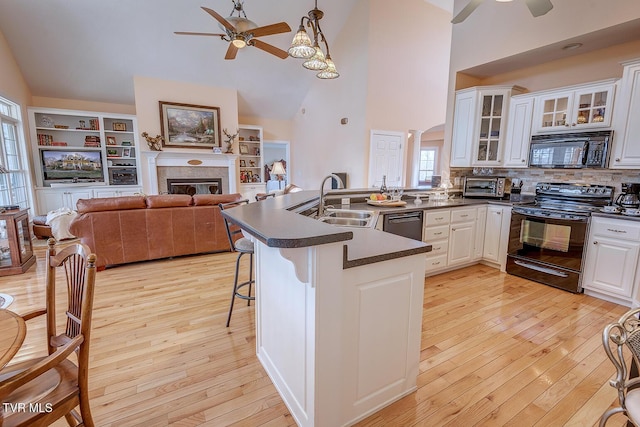 kitchen with decorative light fixtures, black appliances, kitchen peninsula, and white cabinets