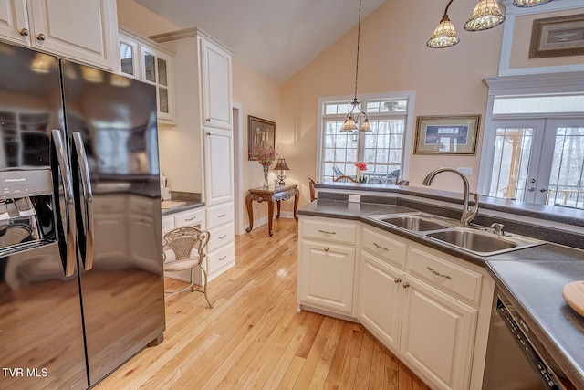 kitchen with a sink, decorative light fixtures, light wood finished floors, and black fridge