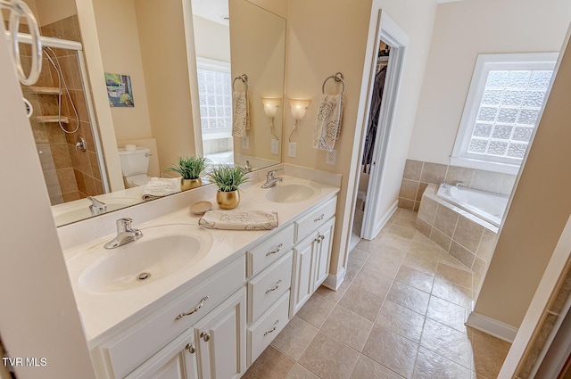 bathroom with a tile shower, toilet, a relaxing tiled tub, and a sink