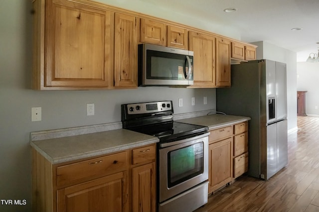 kitchen featuring dark hardwood / wood-style flooring, stainless steel appliances, and an inviting chandelier