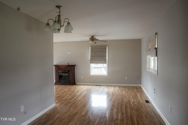 unfurnished living room featuring wood-type flooring and ceiling fan with notable chandelier