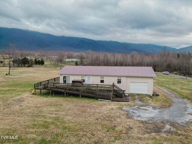 view of front of home featuring a front lawn, a deck with mountain view, and a garage