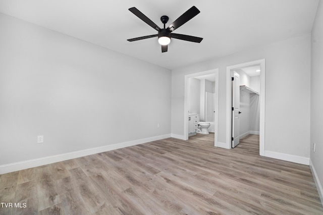 unfurnished bedroom featuring a walk in closet, ceiling fan, light wood-type flooring, connected bathroom, and a closet