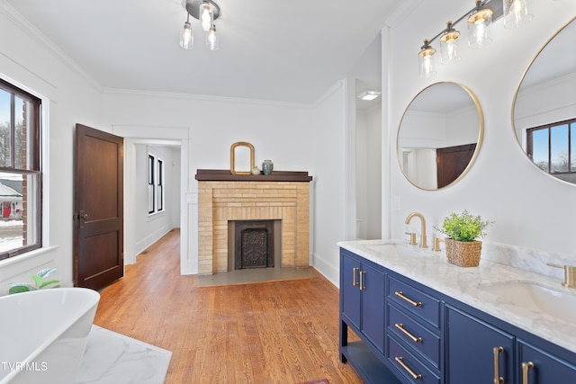 bathroom featuring a fireplace, hardwood / wood-style floors, crown molding, and a washtub