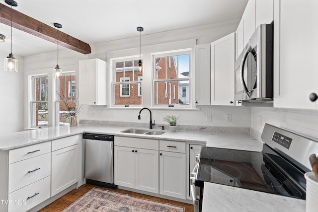 kitchen with white cabinets, hanging light fixtures, sink, appliances with stainless steel finishes, and beamed ceiling