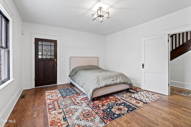 bedroom with multiple windows and dark wood-type flooring