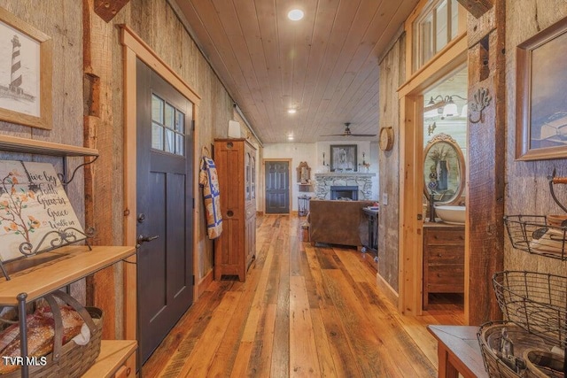 corridor featuring wood-type flooring, wooden ceiling, and wood walls