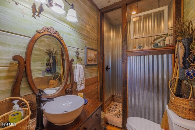 bathroom with toilet, wooden walls, and vanity