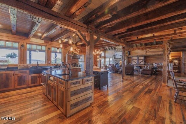 kitchen featuring sink, beamed ceiling, a healthy amount of sunlight, a center island with sink, and wood ceiling