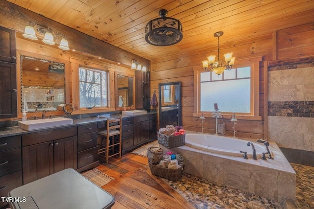 bathroom featuring wooden ceiling, hardwood / wood-style floors, tiled bath, vanity, and a chandelier