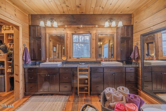 bathroom with wood ceiling, wooden walls, and vanity